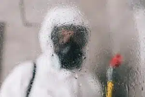 pest control worker standing in respirator in bathroom